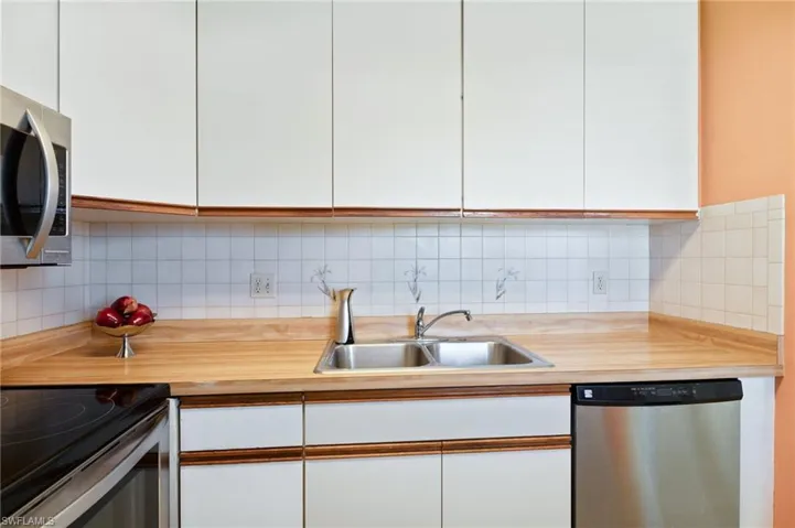 Kitchen featuring butcher block like counters, sink, appliances with stainless steel finishes, backsplash, and white cabinets