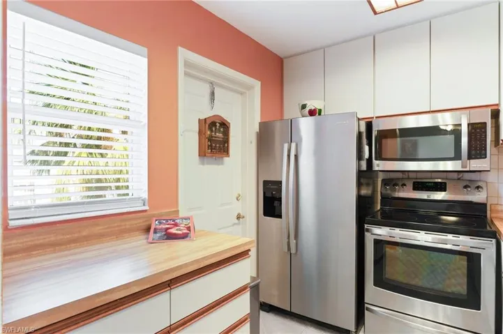 Kitchen featuring white cabinetry, appliances with stainless steel finishes, backsplash, and a healthy amount of sunlight