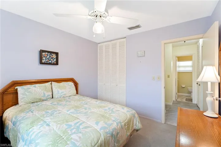 Carpeted bedroom with ceiling fan and a closet