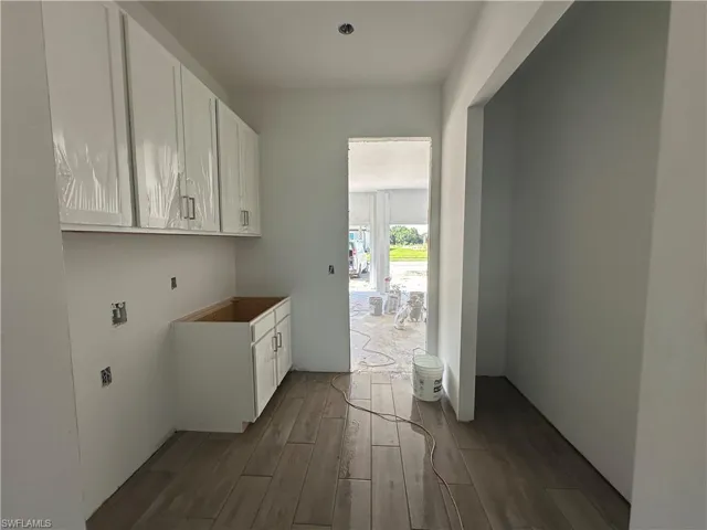 Washroom with hookup for a washing machine, cabinets, and wood-type flooring