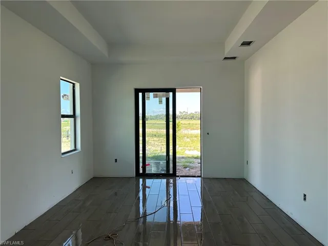 Unfurnished room featuring a tray ceiling and dark hardwood / wood-style floors