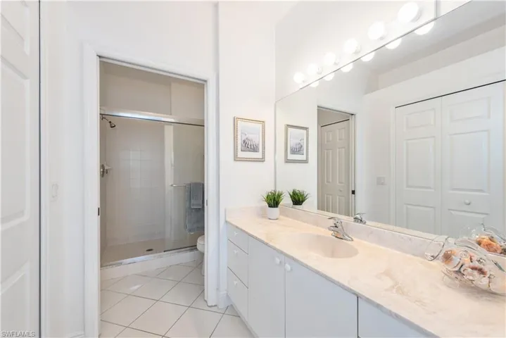 Bathroom featuring a shower with shower door, vanity, toilet, and tile floors