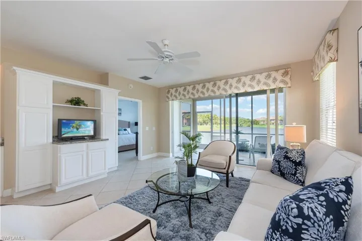 Tiled living room with ceiling fan and a water view