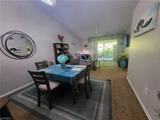 Carpeted dining space with baseboards and vaulted ceiling