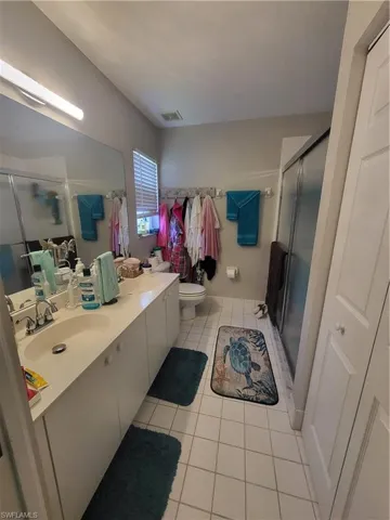 Full bathroom featuring double vanity, a shower stall, and light tile patterned floors