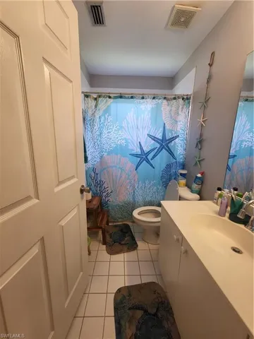Full bath with light tile patterned flooring and vanity