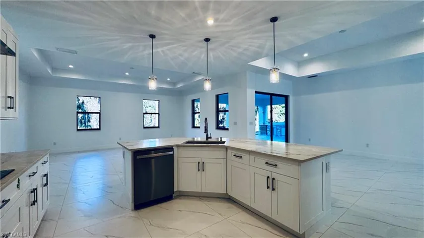 Kitchen with light marble finish flooring, white cabinetry, black appliances, and recessed lighting