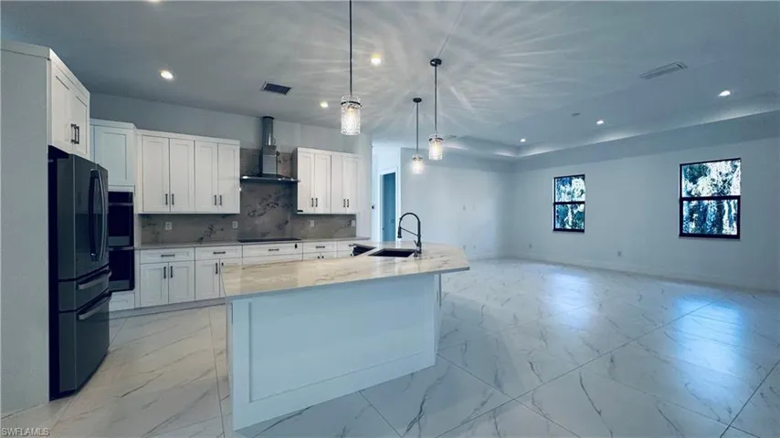 Kitchen with light marble finish flooring, white cabinetry, black appliances, and recessed lighting