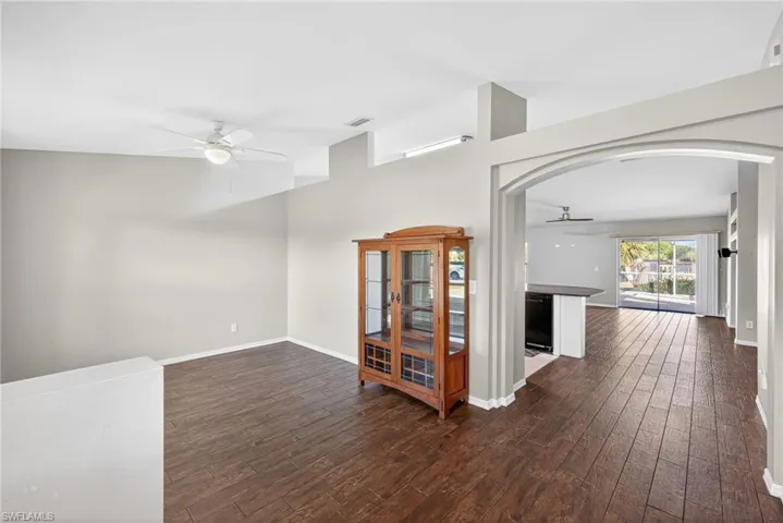 Spare room with a ceiling fan, dark wood-style flooring, and arched walkways