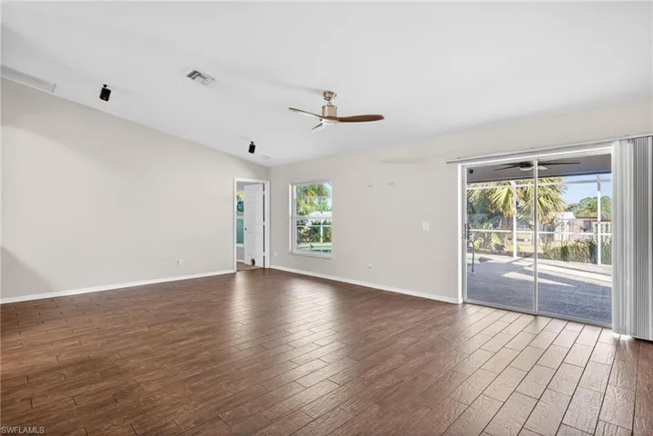 Empty room featuring dark wood-style flooring, ceiling fan, and lofted ceiling