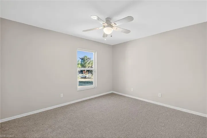 Carpeted spare room featuring baseboards and a ceiling fan