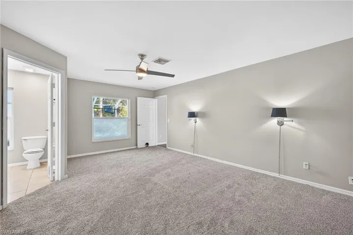 Unfurnished bedroom with carpet, ceiling fan, and ensuite bath