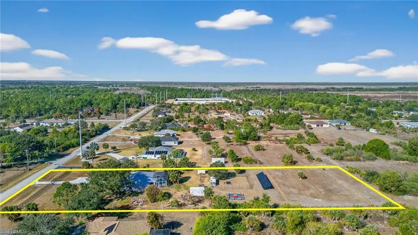 Aerial perspective of suburban area with property parcel outlined and a heavily wooded area