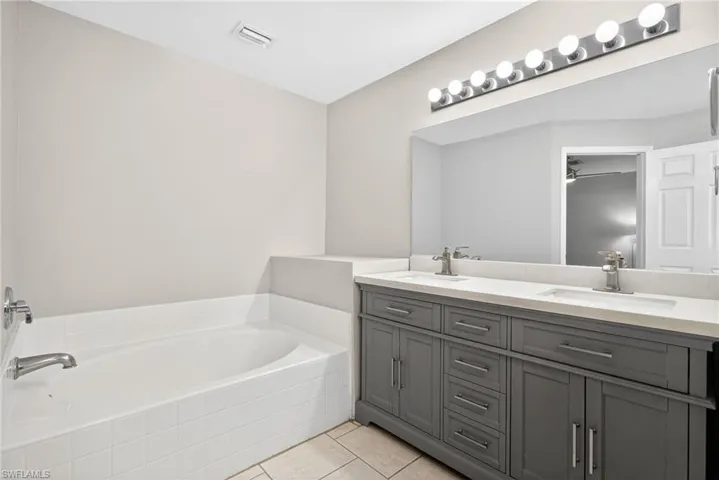 Bathroom featuring double vanity, a garden tub, and light tile patterned floors