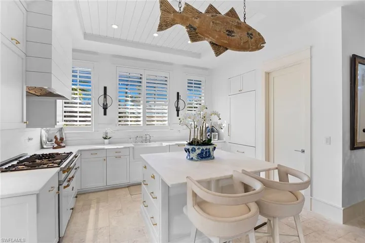Kitchen with high end stove, a kitchen bar, a kitchen island, white cabinets, and a wooden tray ceiling