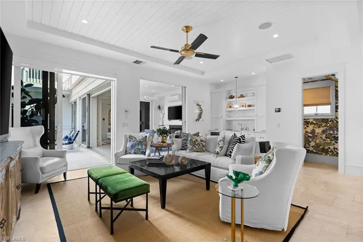 Living area featuring a wood tray ceiling, a ceiling fan, recessed lighting, and light stone finish flooring