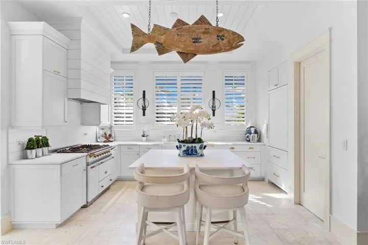 Kitchen featuring a kitchen bar, white cabinetry, and light stone countertops