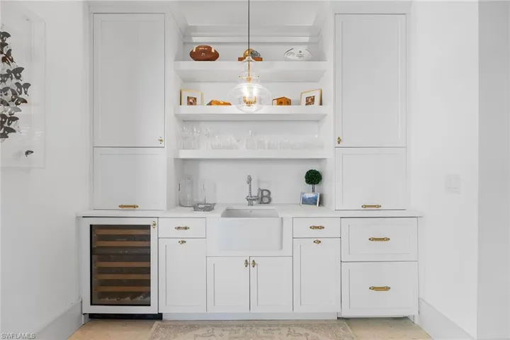 Indoor wet bar featuring beverage cooler, white cabinets, and open shelves