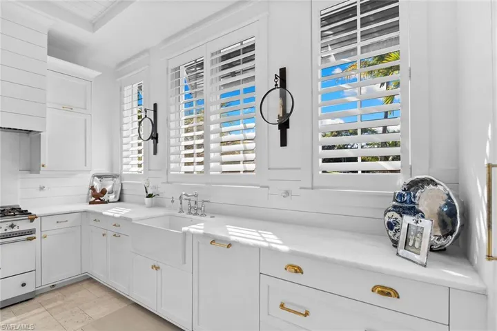 Kitchen featuring white cabinets, white range with gas stovetop, light stone countertops, and extractor fan