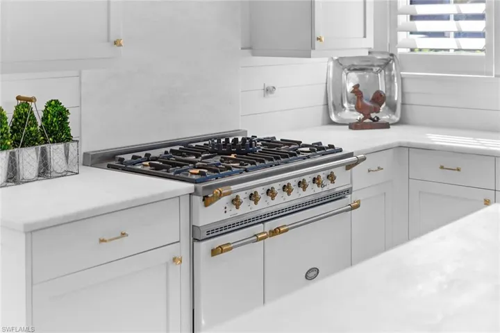 Kitchen featuring range with two ovens, white cabinetry, and light stone countertops