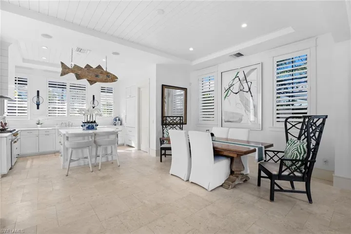 Dining room with plenty of natural light, light stone finish flooring, a wooden tray ceiling, and recessed lighting