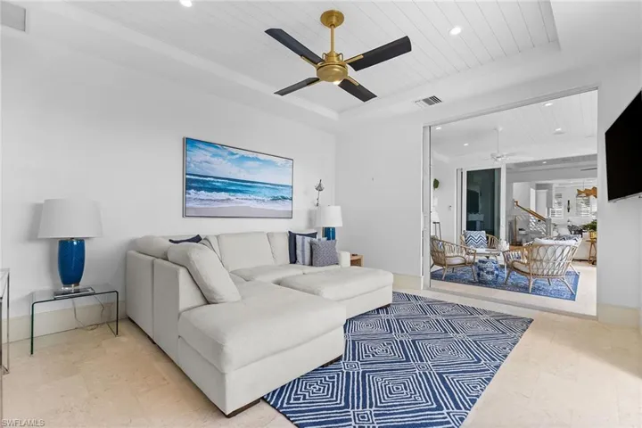 Living room with a ceiling fan, a wood tray ceiling, and recessed lighting