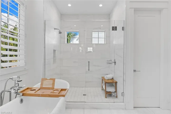 Bathroom featuring a stall shower, a freestanding tub, and recessed lighting