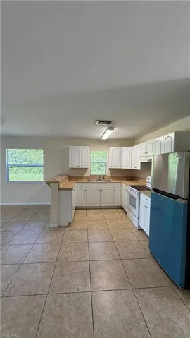 Kitchen featuring white cabinetry, light-toned countertops, and tile flooring