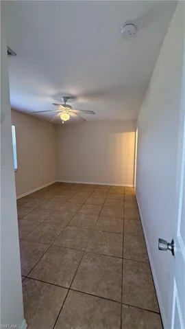 Spacious room featuring neutral tone tile flooring and a ceiling fan with integrated lighting