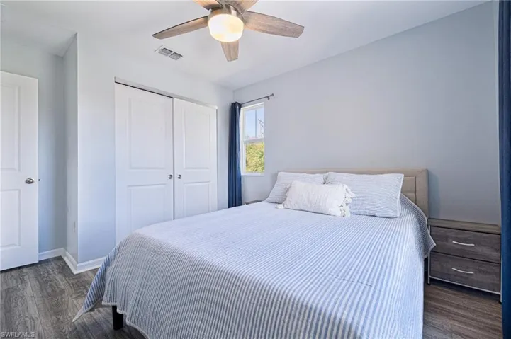 Bedroom with ceiling fan, dark hardwood / wood-style floors, and a closet