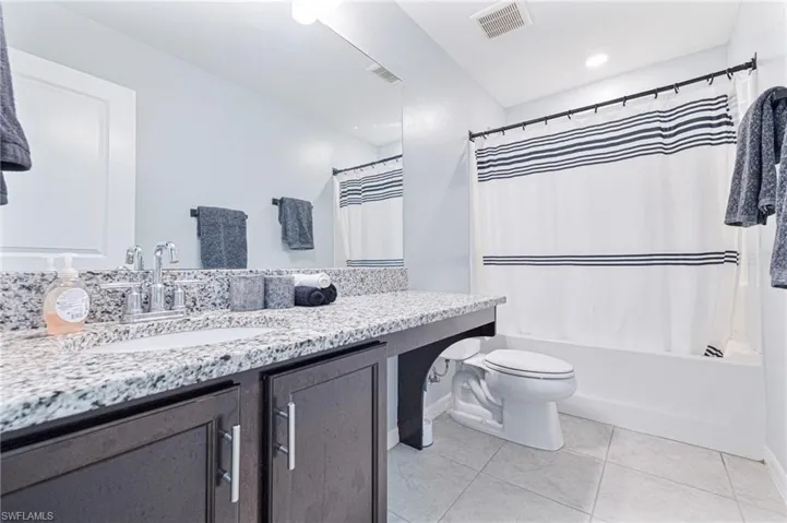 Full bathroom featuring shower / bath combination with curtain, tile patterned floors, toilet, and vanity