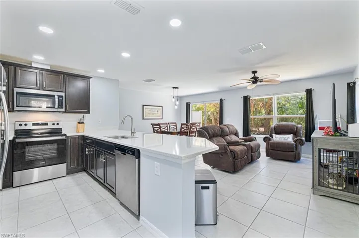 Kitchen featuring light tile patterned flooring, appliances with stainless steel finishes, kitchen peninsula, and sink