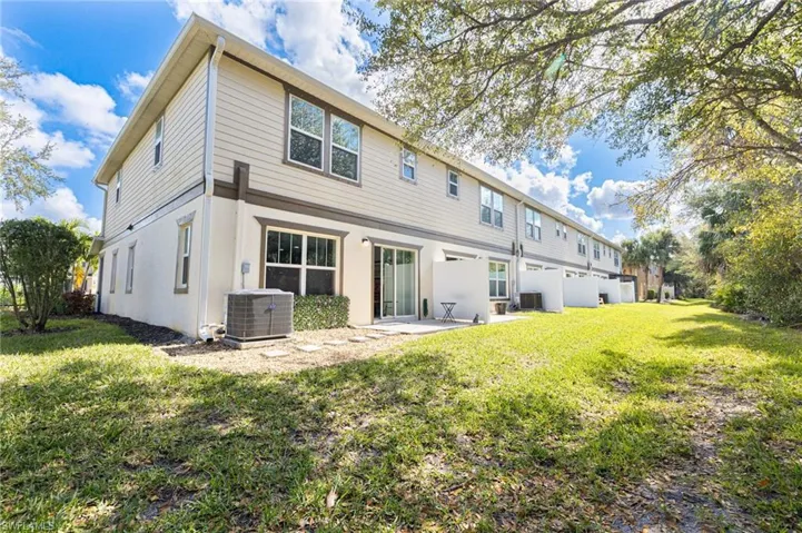 Rear view of property with central AC unit, a lawn, and a patio
