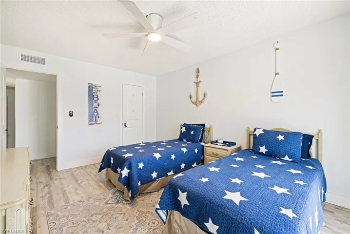 Bedroom featuring light wood-type flooring, a textured ceiling, and ceiling fan