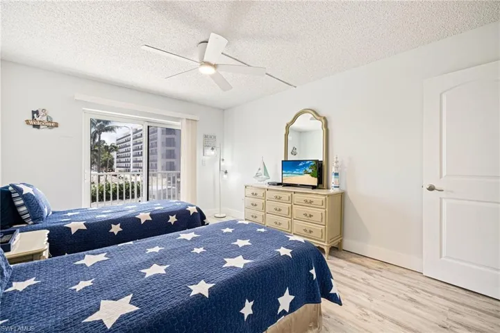 Bedroom with a textured ceiling, light wood-style flooring, a ceiling fan, and access to exterior