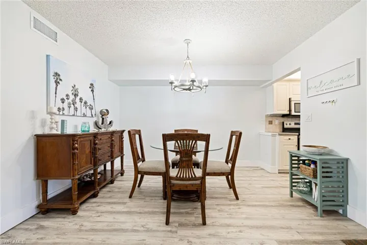 Dining space featuring a chandelier, light wood-style floors, and a textured ceiling
