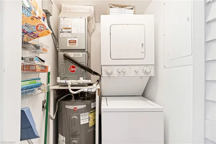 Laundry room with water heater, estacked washer and dryer, and heating unit