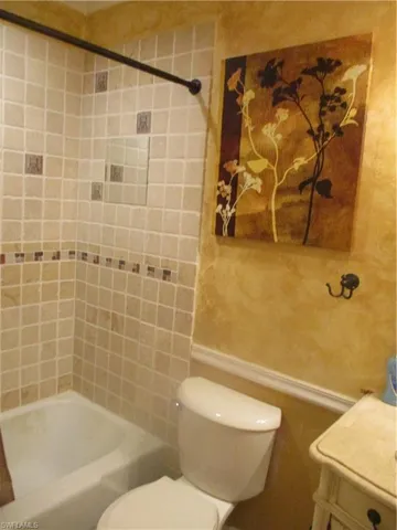 Full bathroom featuring tiled shower / bath combo, vanity, and toilet