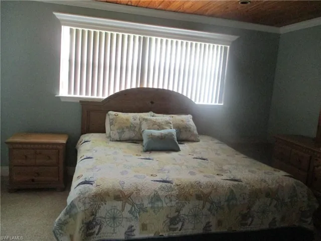 Bedroom with carpet floors, ornamental molding, and wooden ceiling