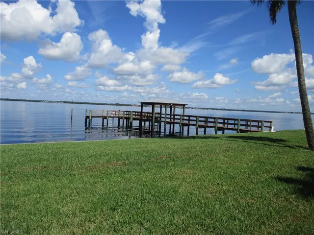 View of dock featuring a lawn and a water view