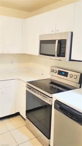 Kitchen featuring stainless steel appliances, white cabinets, and light tile patterned floors