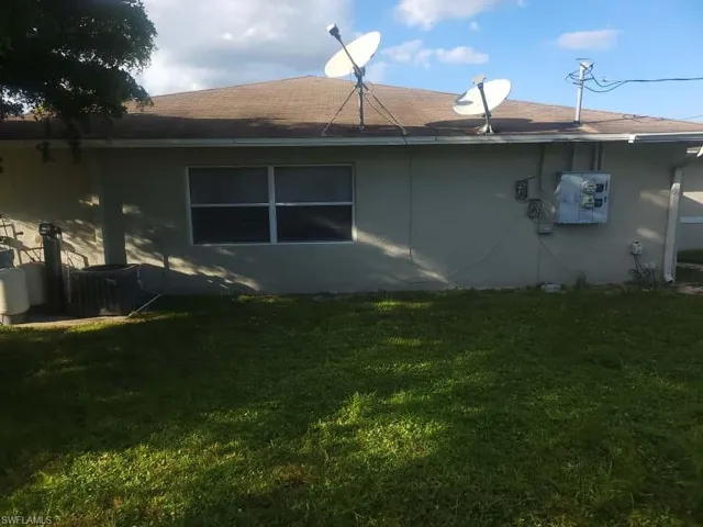 View of side of home with a yard and roof with shingles