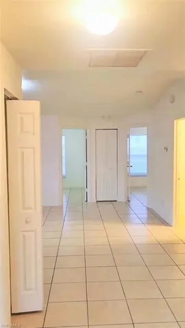 Corridor with light tile patterned floors and attic access