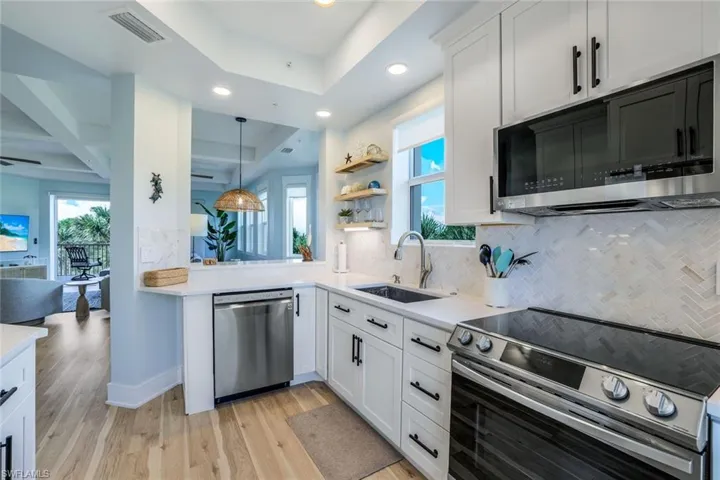 Kitchen featuring stainless steel appliances, white cabinets, backsplash, light wood finished floors, and recessed lighting