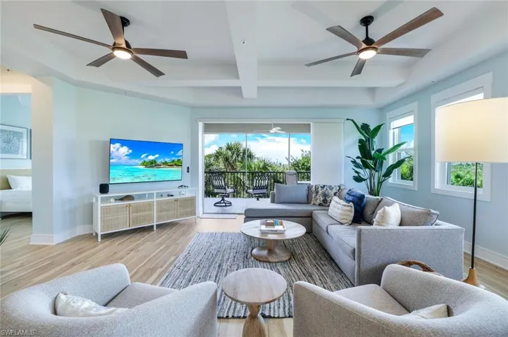 Living room with light wood-style floors, beamed ceiling, a ceiling fan, and coffered ceiling