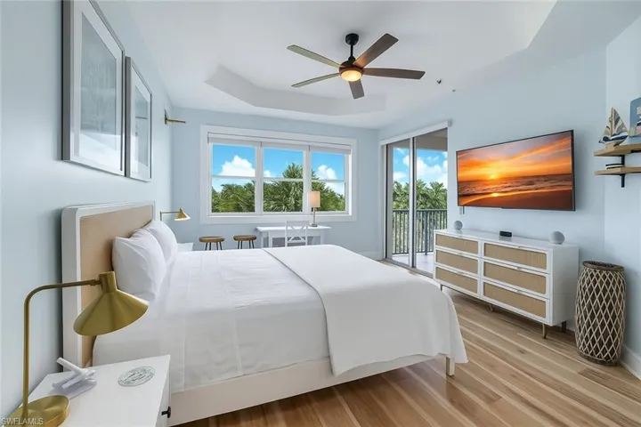 Bedroom featuring a raised ceiling, light wood-type flooring, ceiling fan, and access to exterior