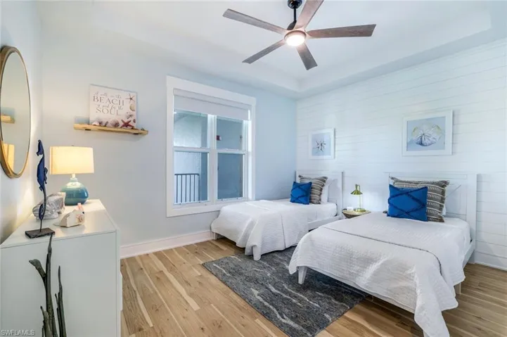 Bedroom featuring a tray ceiling, light wood finished floors, and ceiling fan