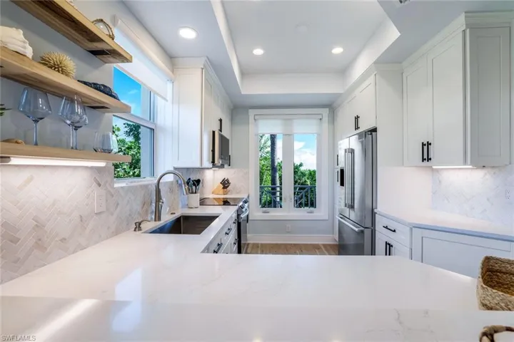 Kitchen featuring backsplash, white cabinetry, open shelves, light stone counters, and recessed lighting