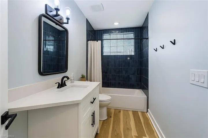 Full bath featuring vanity, shower / bath combo, and light wood finished floors