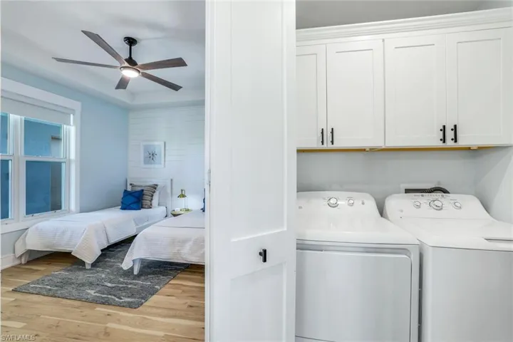 Washroom featuring light wood-type flooring, independent washer and dryer, cabinet space, and ceiling fan